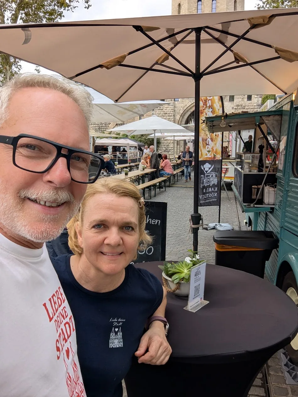 Boris und Dorothee lächeln am Stehtisch vor dem Citroën HY auf einem Kölner Markt